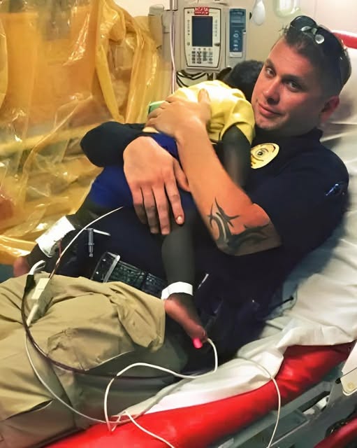 Picture captures a police officer comforting a scared toddler in the hospital